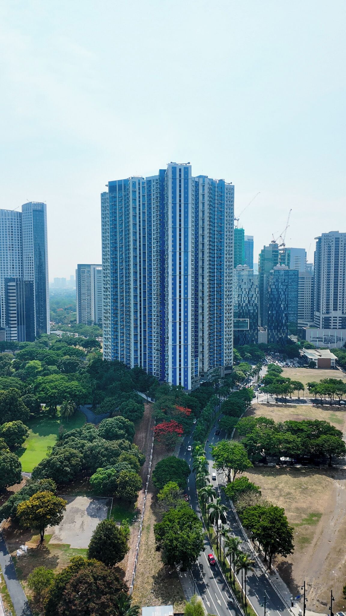 A high-rise building with a modern architectural design, surrounded by greenery and other high-rise buildings.