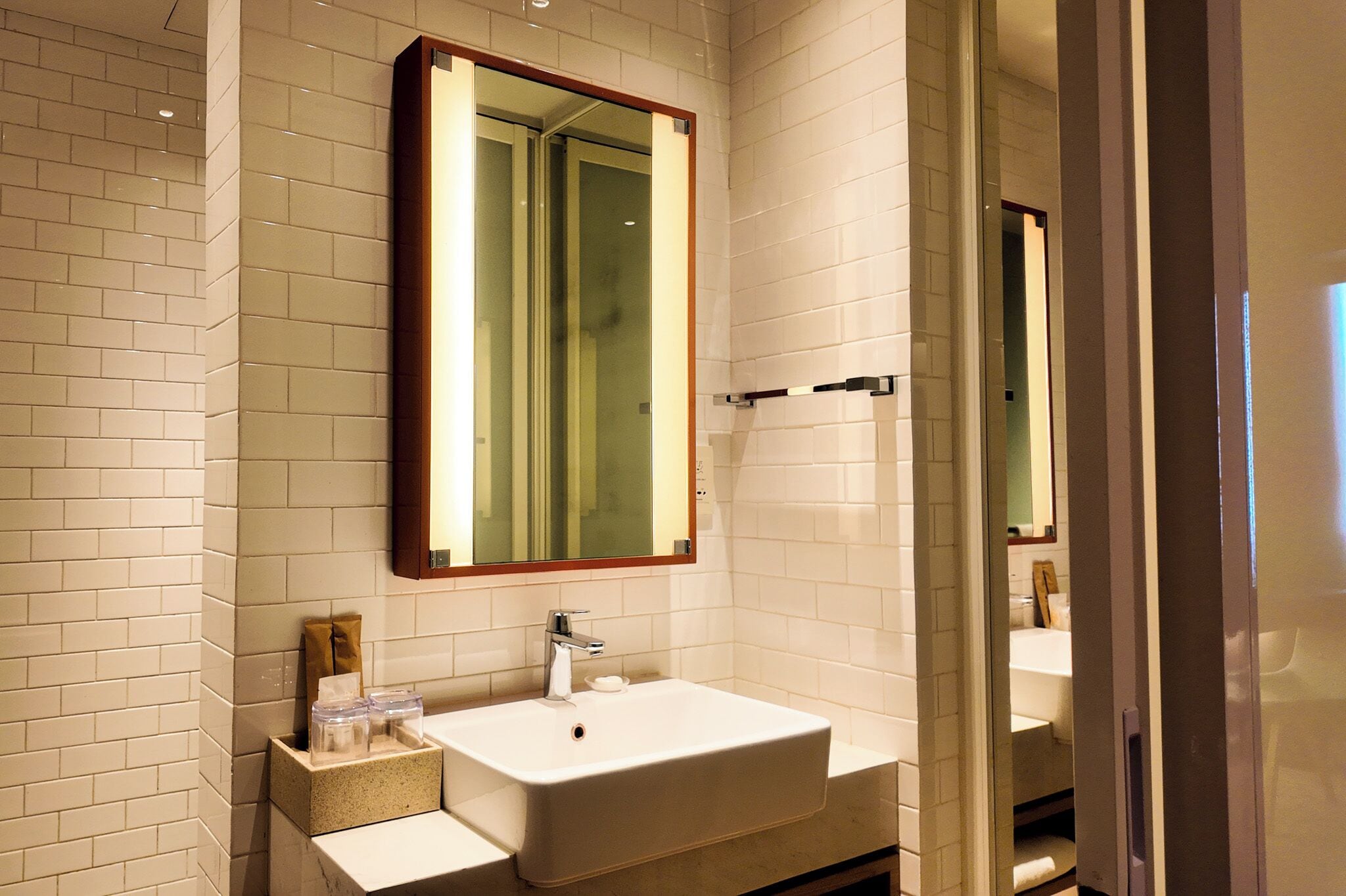 Une salle de bain avec un lavabo blanc, un miroir et un porte-serviettes.