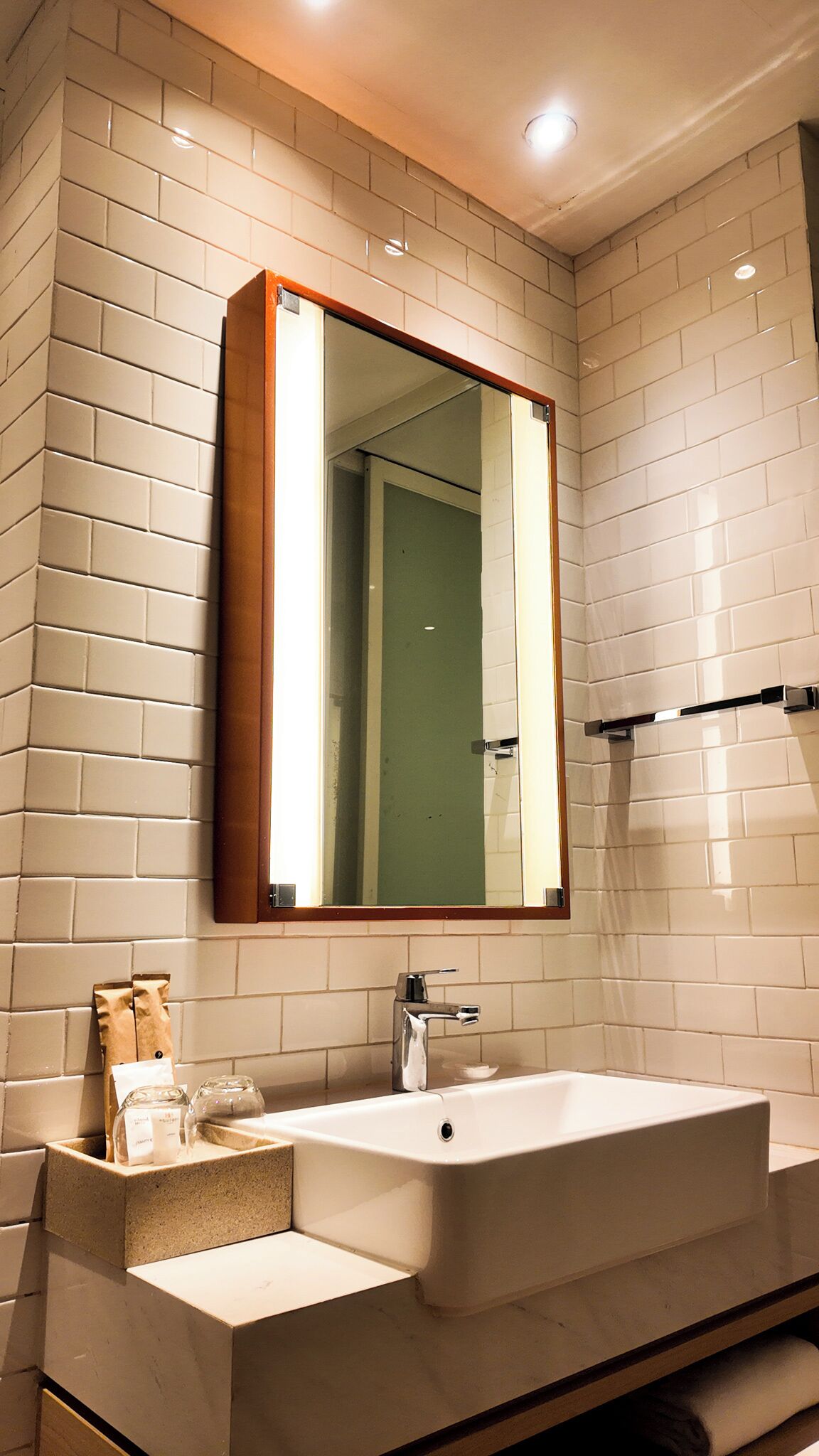 A bathroom with a large mirror, a sink, and a towel rack.