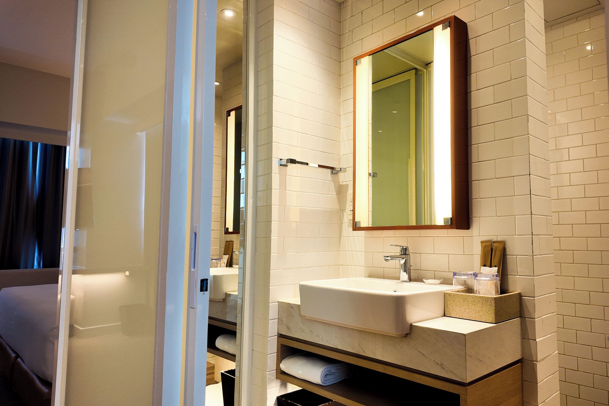 A modern bathroom with a large mirror, a sink, and a towel rack.