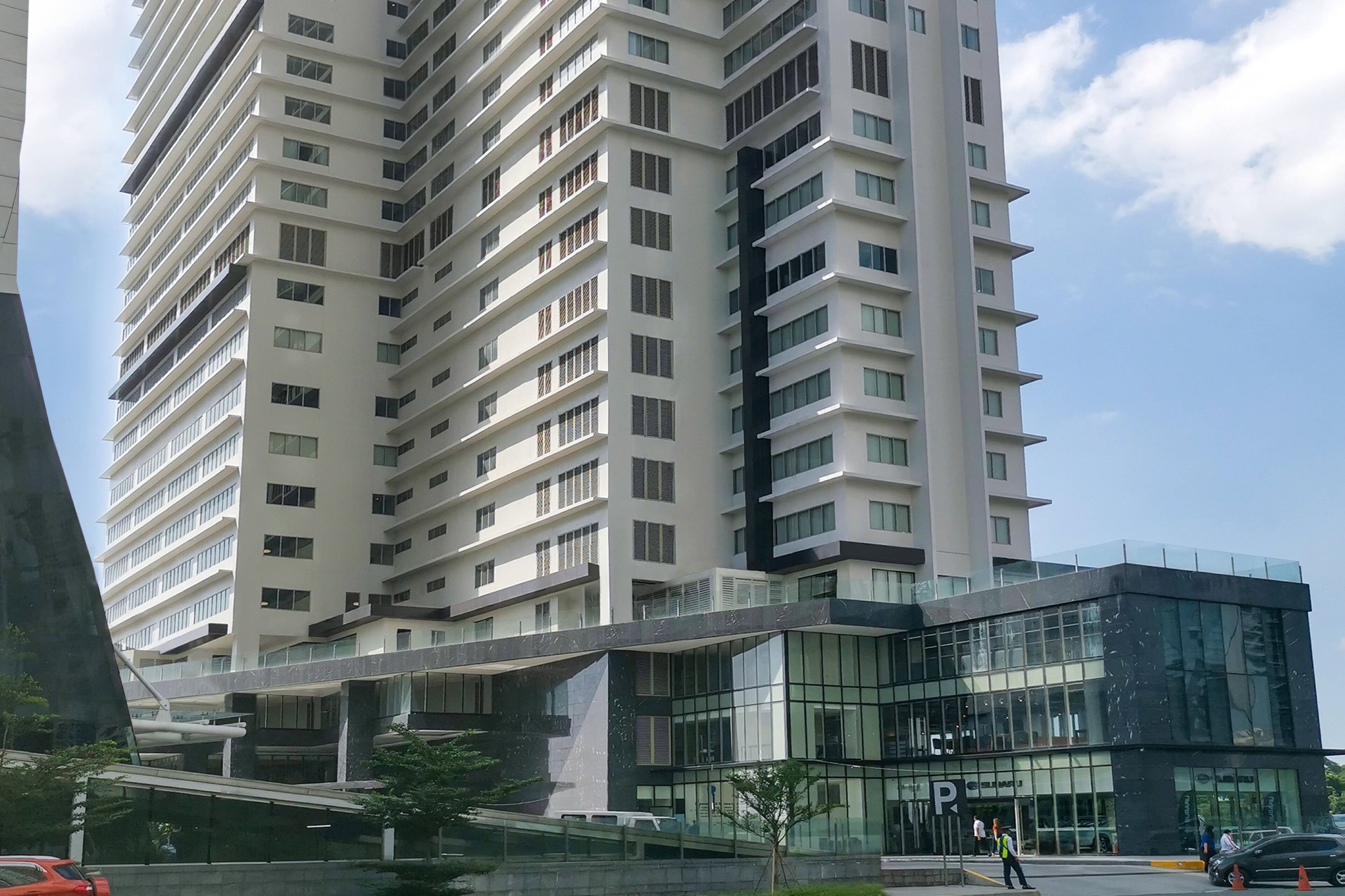 A modern high-rise building with multiple floors, large windows, and a glass entrance area.