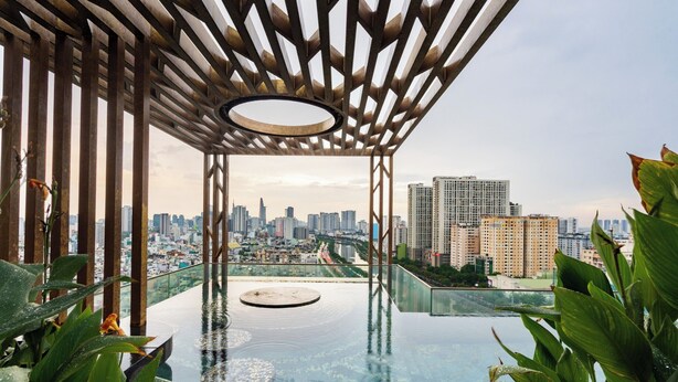 An infinity pool with a city view, surrounded by greenery and a wooden pergola structure. - 3BR APT D1Mension (Ho Chi Minh City)