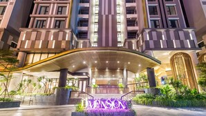 A modern hotel entrance with a curved canopy, a landscaped area with plants, and the name 'IMPTSON' illuminated on the facade. - 3BR APT D1Mension (Ho Chi Minh City)