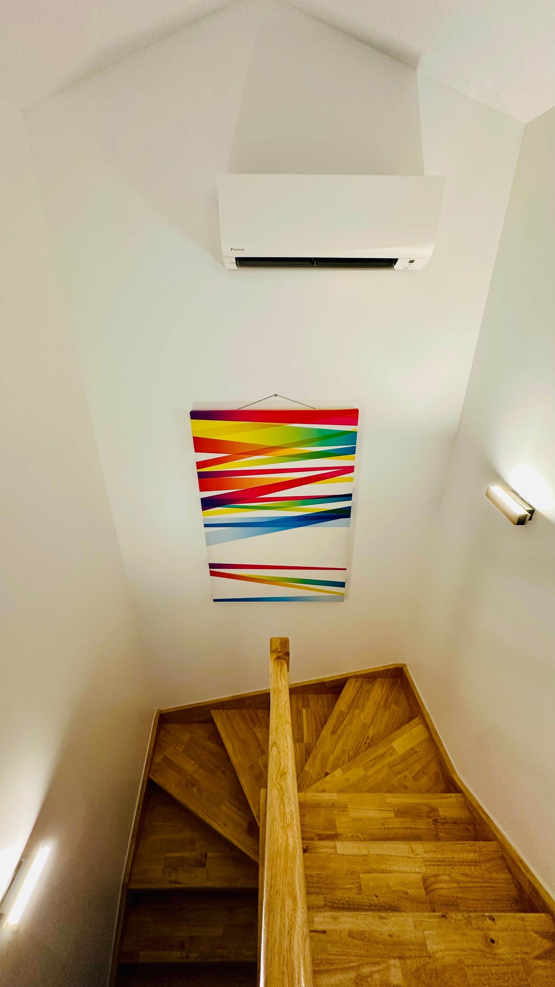 Eine Treppe mit Holzdielen und einem farbenfrohen, abstrakten Gemälde an der Wand.