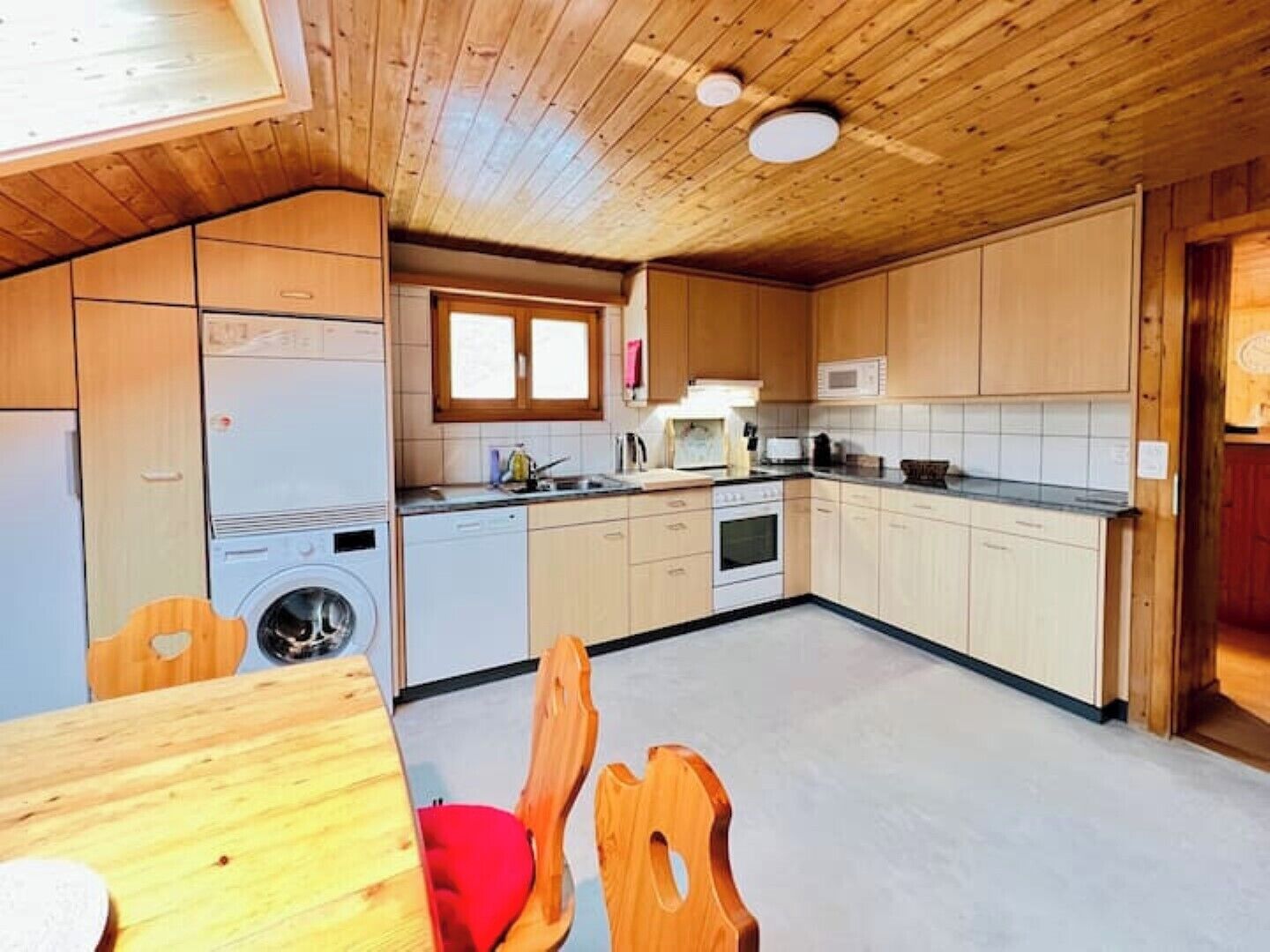 Une cuisine compacte avec des meubles en bois, un lave-linge, un four à micro-ondes et un évier.
