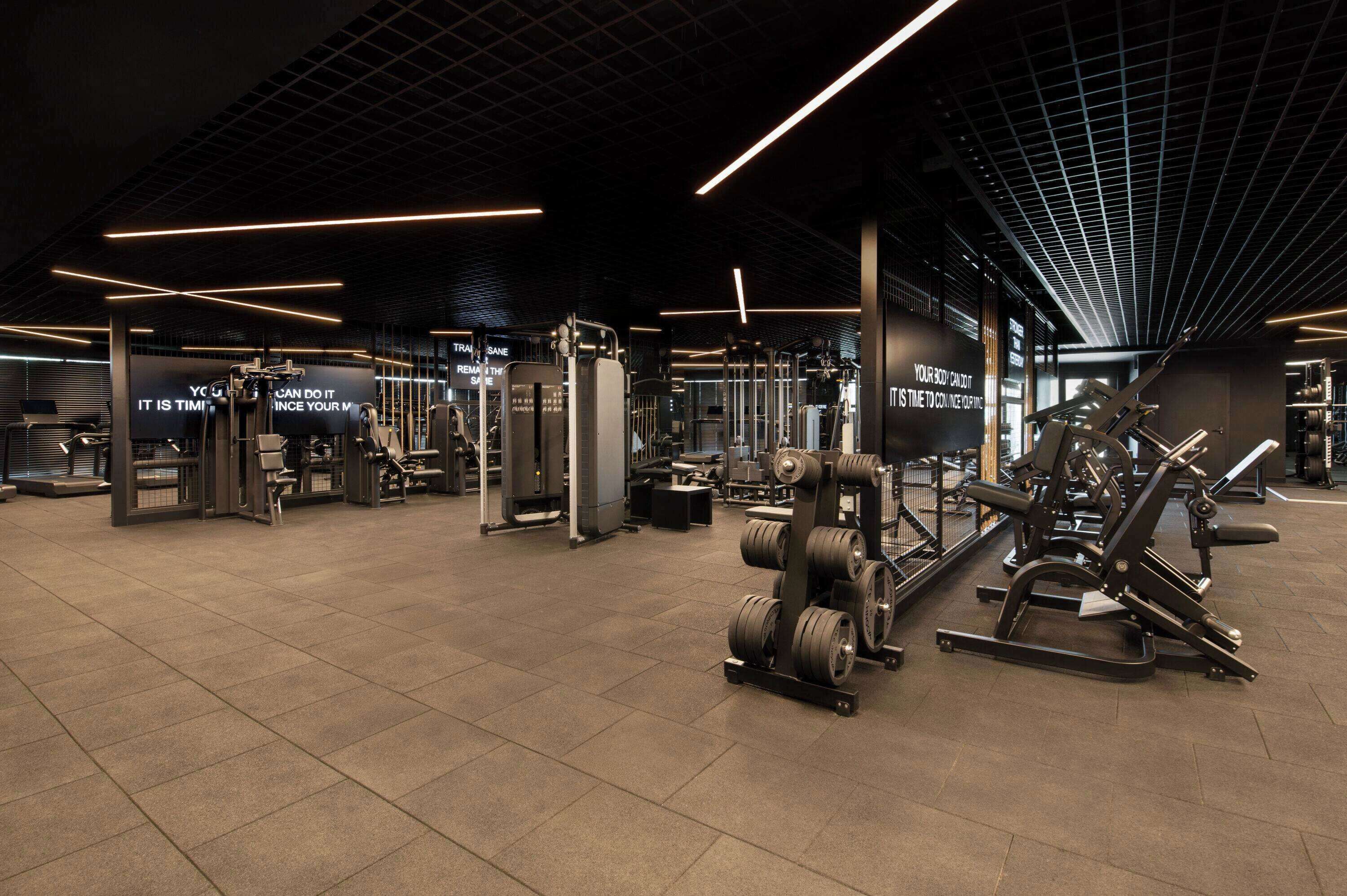 Un gimnasio moderno con diverso equipamiento de levantamiento de pesas y letreros motivacionales.