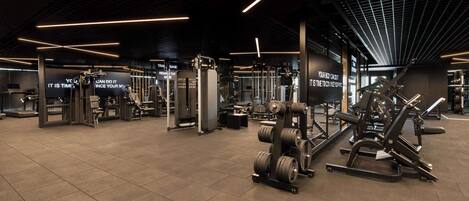 Un gimnasio moderno con diverso equipamiento de levantamiento de pesas y letreros motivacionales.