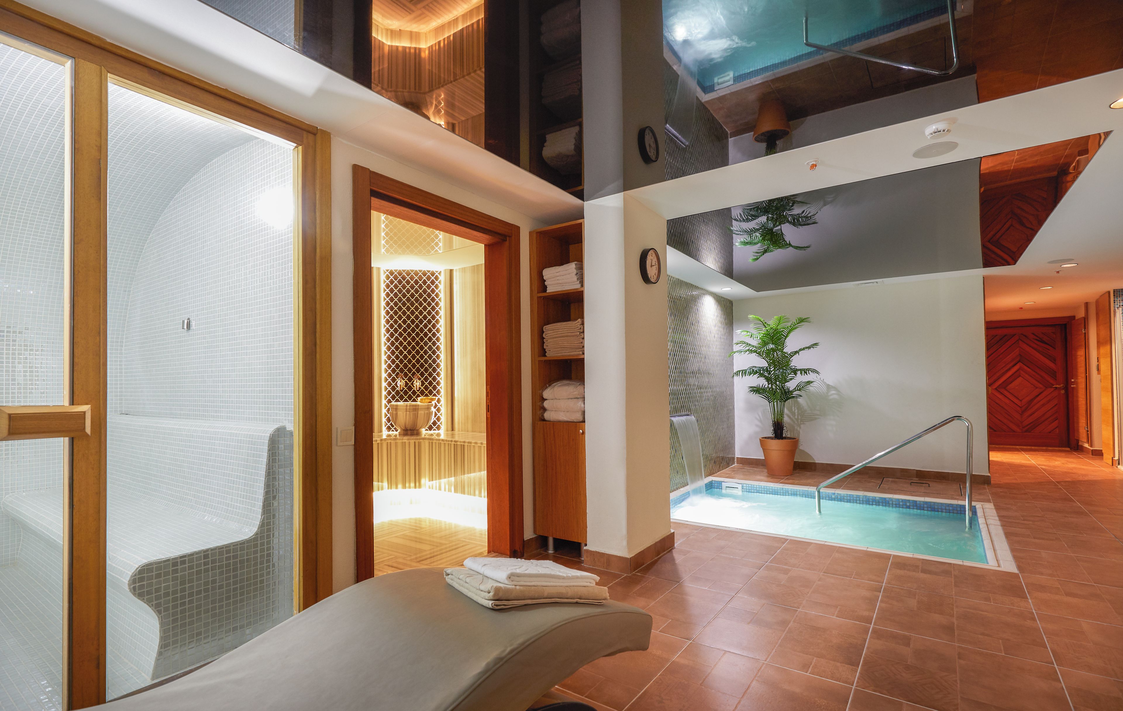 A spa area with a pool, a seating area with towels, and a wooden staircase.