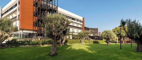 Un edificio moderno con estructura de varios pisos, zona de estar al aire libre y césped bien cuidado.