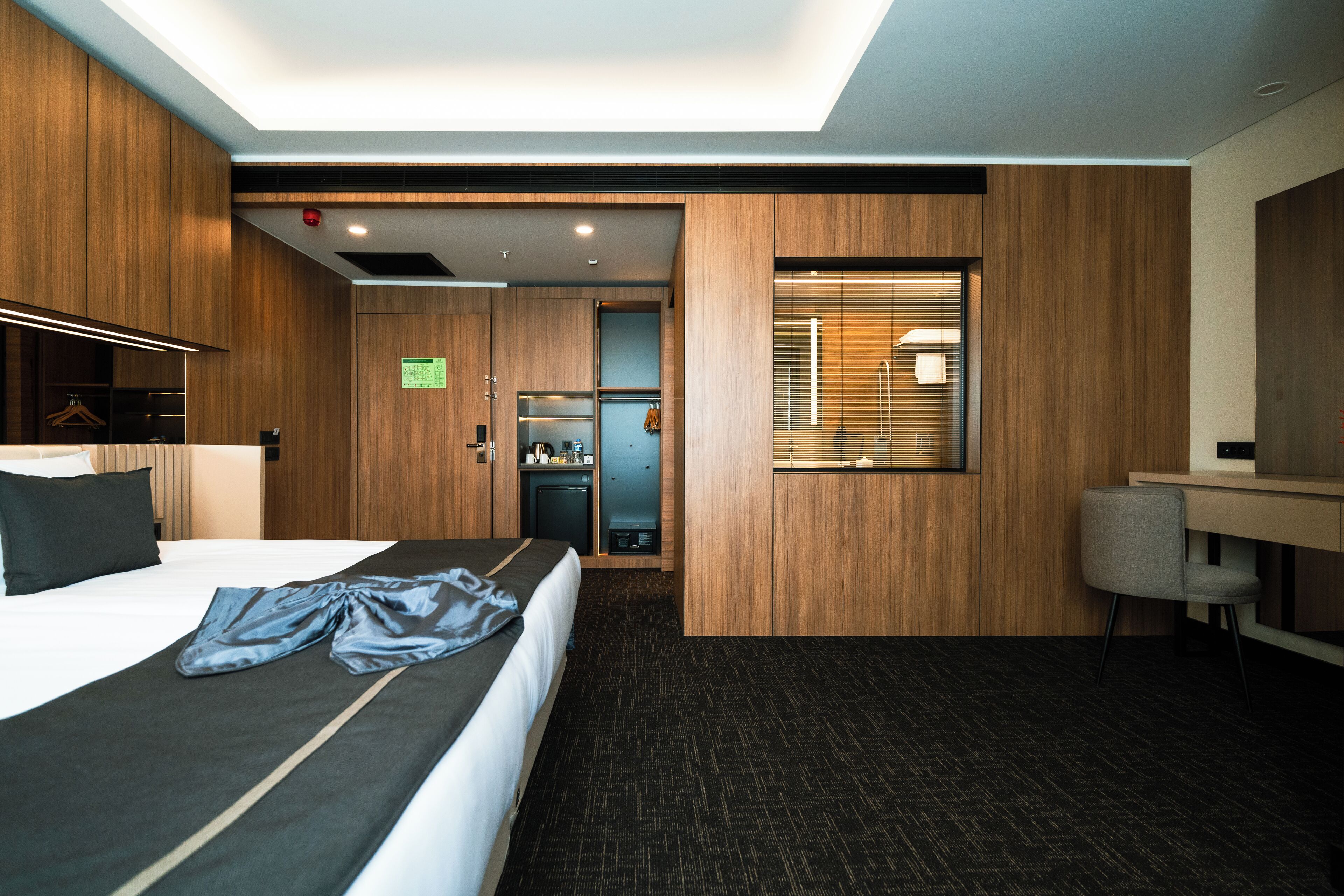 Una habitación de hotel moderna con una cama grande, un escritorio y una kitchenette compacta.