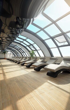 Una habitación iluminada por el sol con techo curvo y filas de sillones.