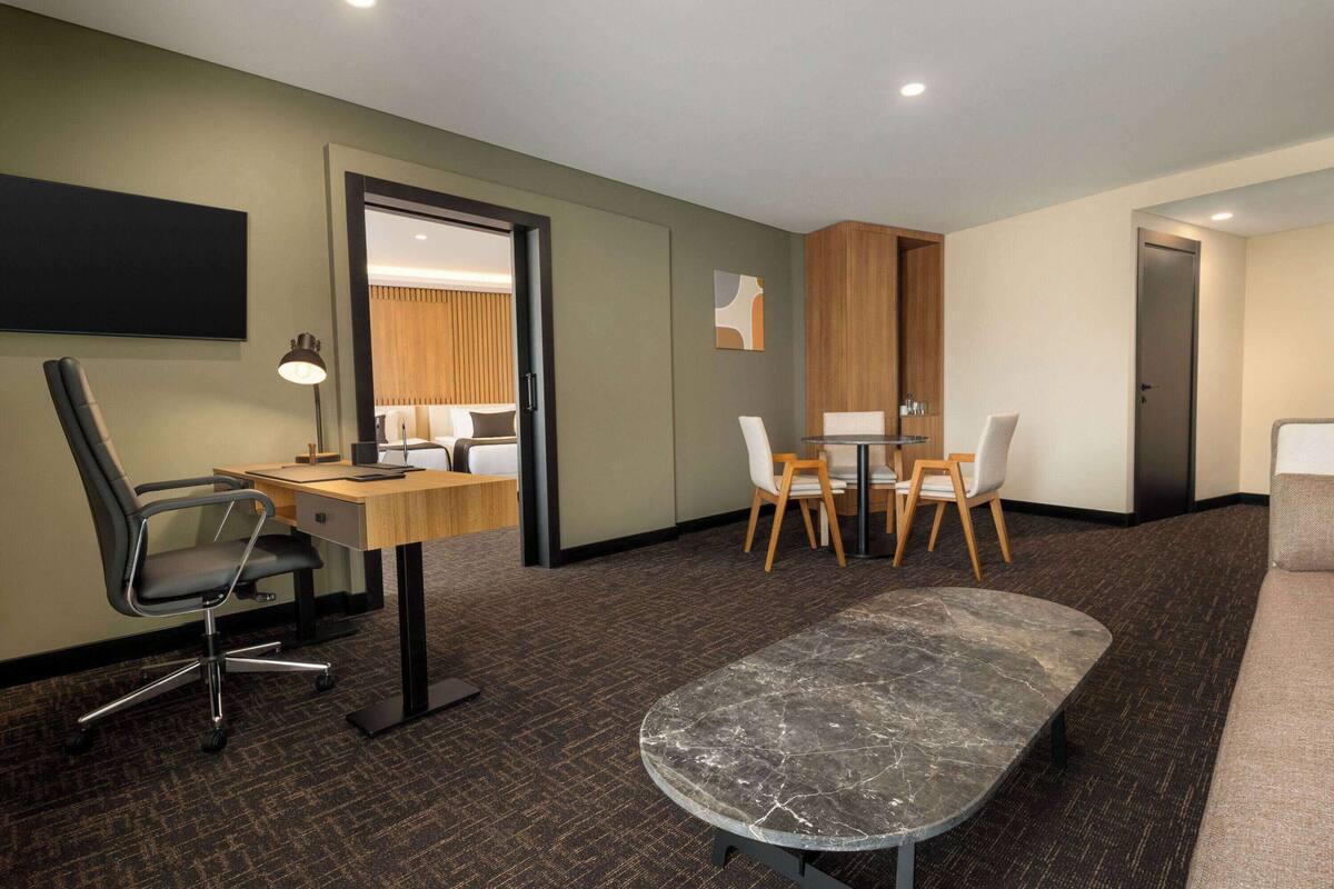 Une chambre d’hôtel équipée d’un bureau, d’un fauteuil de bureau, d’une petite table ronde et d’un canapé.