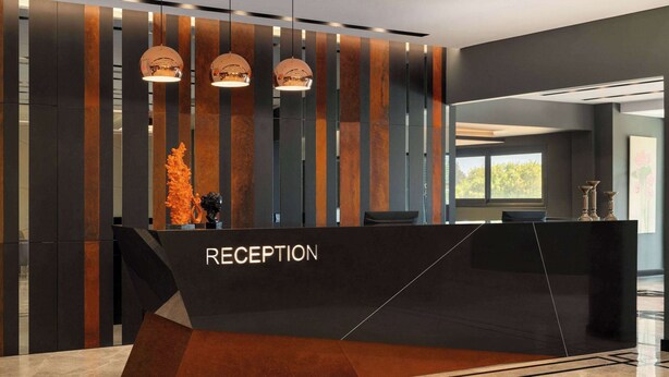 Un comptoir d’accueil au design moderne, avec une palette de couleurs composée de noir et de marron et un motif géométrique.
