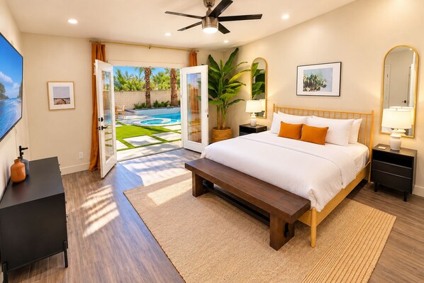 A bedroom with a bed, bedside tables, a bench, a desk, and a large window.