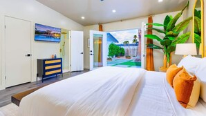 A modern bedroom with a large bed, a ceiling fan, and a view of a garden through an open door. - 25% Off Sep 17-20 Perfect 4 Families Pool, Jacuzzi (Palm Springs)