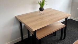 A small wooden table with a bench, a potted plant, and a black floor lamp. - The Heilan` Coo Apartment (Argyll and Bute Council)