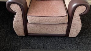 A brown armchair with a cushion featuring a dog illustration. - The Heilan` Coo Apartment (Argyll and Bute Council)