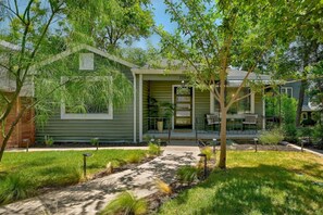 A modern house with a covered porch, a small garden, and a pathway leading to the entrance. - SoCo BoHo Bungalow | Main House (Austin)