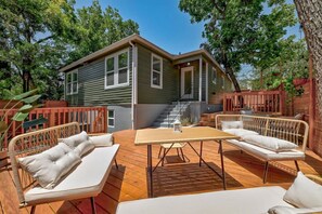 A wooden deck with outdoor furniture, a small house with a porch, and a staircase leading to the house. - SoCo BoHo Bungalow | Main House (Austin)