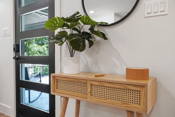 A wooden console table with a plant and a lamp, positioned next to a black-framed door with glass panels.