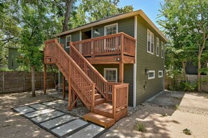 A two-story wooden house with a wooden staircase leading to a balcony.