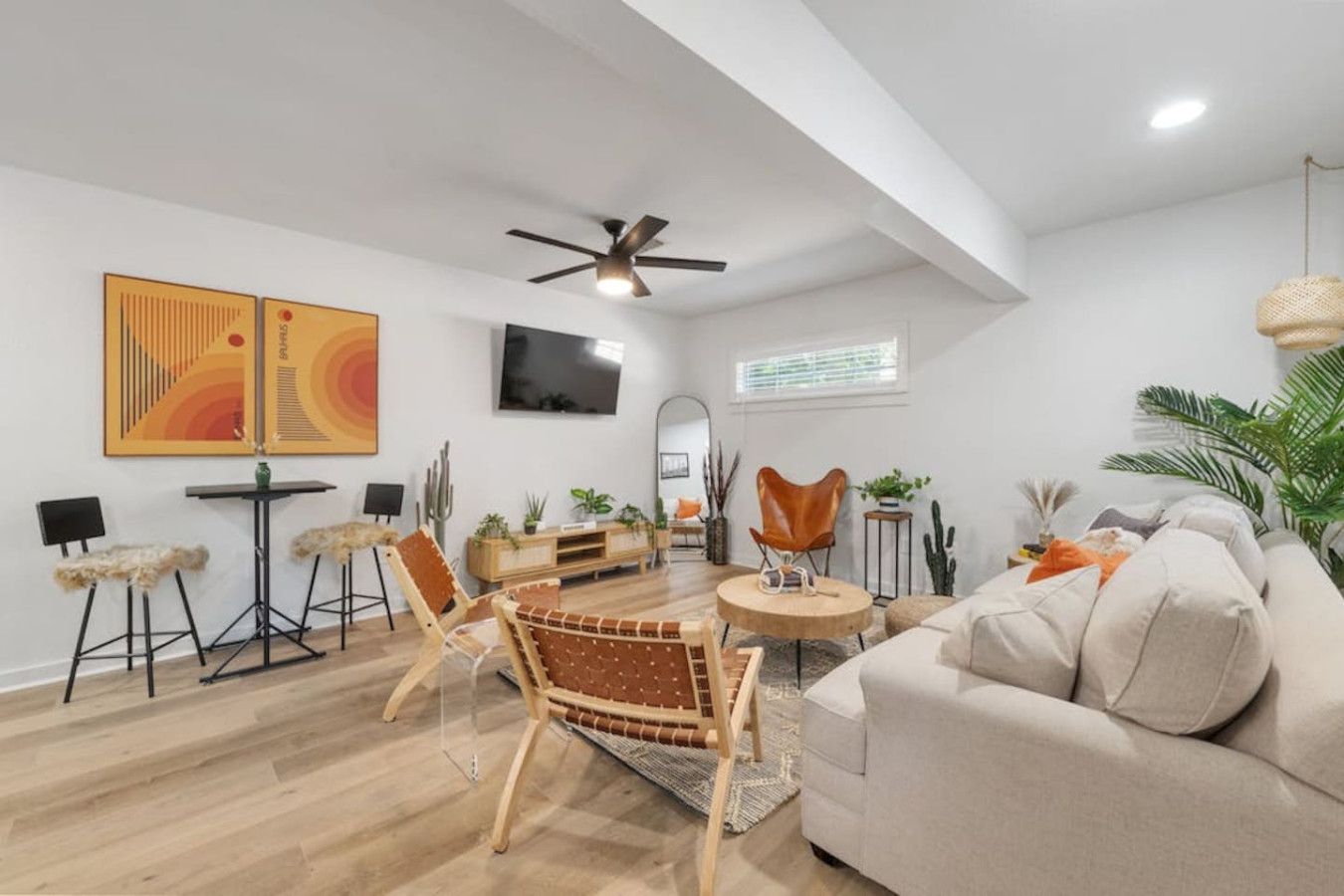 Un salon spacieux avec un plafond haut, un ventilateur de plafond, un téléviseur à écran plat, un canapé, une table basse et un coin repas avec des chaises et une petite table.