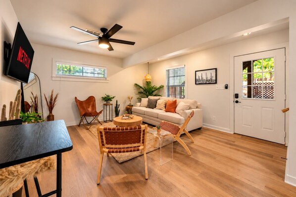 A living room with a sofa, chairs, a coffee table, a TV, and a ceiling fan.
