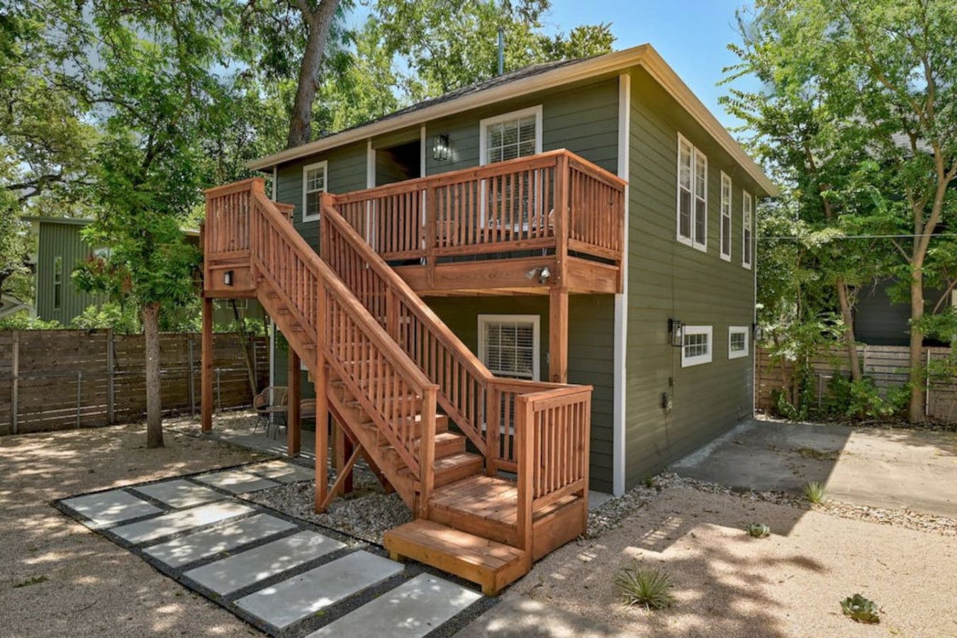 A two-story wooden house with a wooden staircase leading to a balcony.