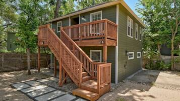 A two-story wooden house with a wooden staircase leading to a balcony.