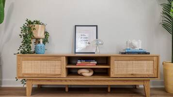 A wooden console table with wicker storage compartments, a framed picture, and decorative items.