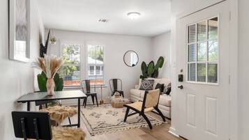 Uma sala de estar moderna com sofá, cadeiras, mesa de centro e área de jantar com mesa e cadeiras.
