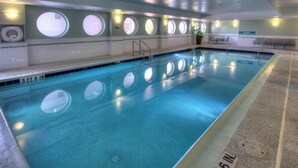 An indoor swimming pool with clear water, a 3 ft 6 in depth, and circular windows along the walls.