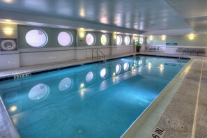 Una piscina interna con acqua cristallina, profonda 1 metro e 12 centimetri, e finestre circolari lungo le pareti.