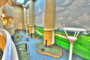 A miniature golf course with green fairways, sand traps, and a white table with a net.