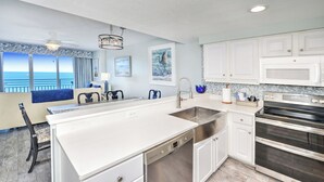 A modern kitchen with a central island, stainless steel appliances, and a view of the ocean. - Oceanfront | King + Balcony +Jetted Soaking Tub (Daytone Beach)