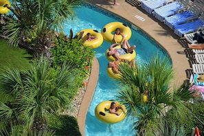 A swimming pool with inflatable rings, lounge chairs, and palm trees. - Oceanfront | King + Balcony +Jetted Soaking Tub (Daytone Beach)