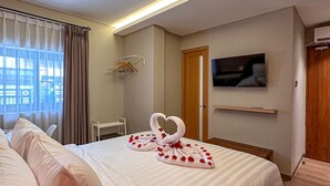 A hotel room with a large bed, a TV mounted on the wall, and a window with curtains. - Lugano Arte Homestay (Jakarta)