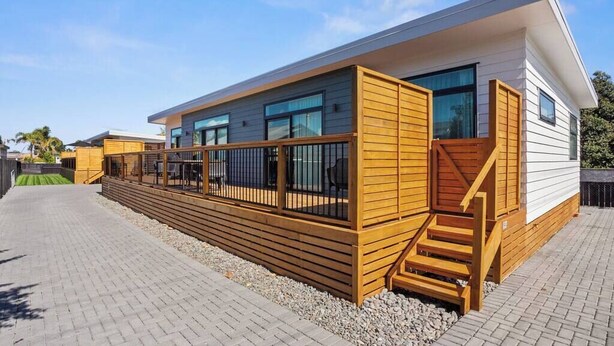 A modern building with a wooden deck, a staircase, and a clear sky.