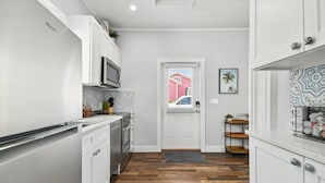 A modern kitchen with white cabinetry, a microwave, and a patterned backsplash. - Downtown Dunedin Hideaway / Easy Walk to Downtown! (Dunedin)