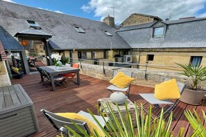 A covered outdoor patio with seating and a table, stone walls, and a sloped roof.