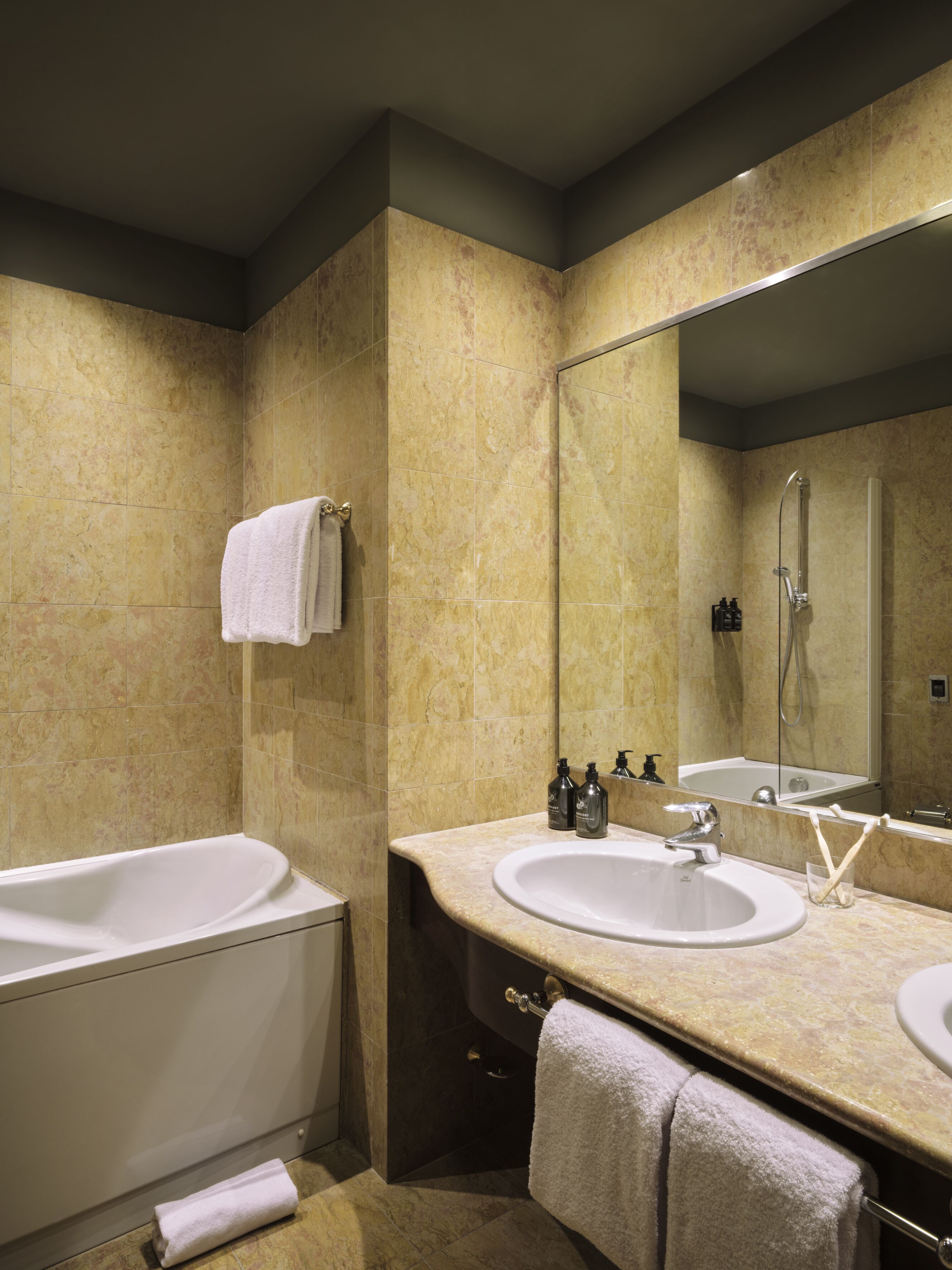 Ein modernes Badezimmer mit einer Badewanne, zwei Waschbecken, einem großen Spiegel und einer Dusche.