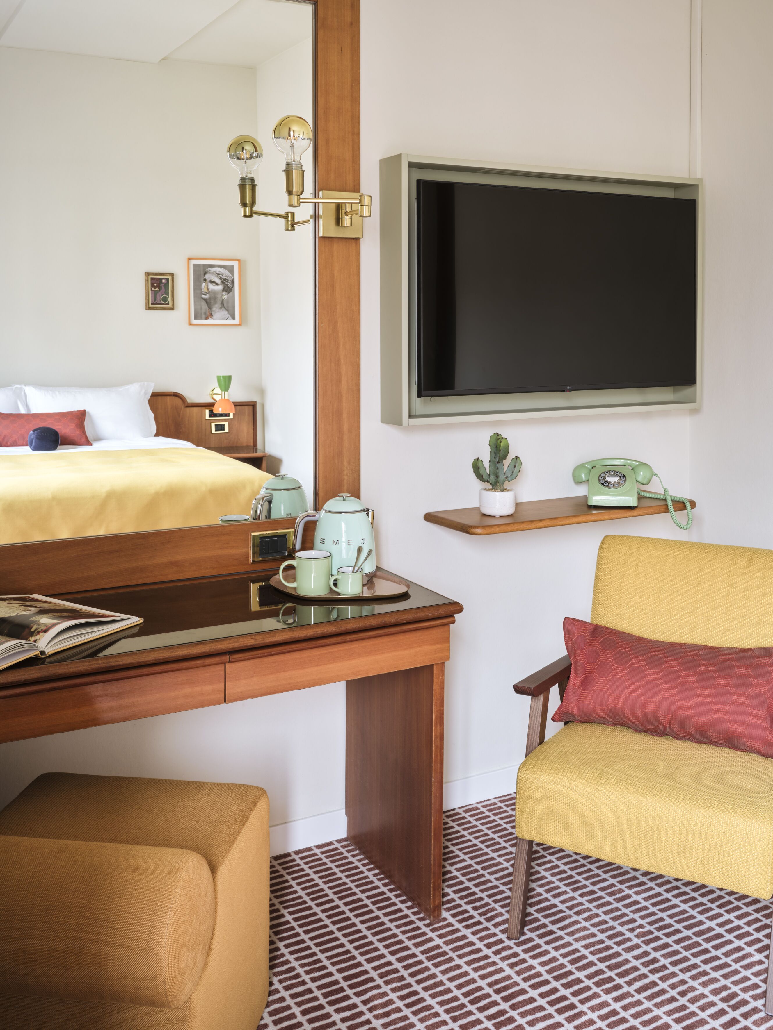 A hotel room with a bed, a desk with a telephone, a television, and a chair.