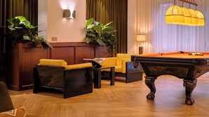 A billiards table in a room with a pool table, a sofa, a chair, and a lamp. - Max Brown Hotel Missori, part of Sircle Collection (Milan)