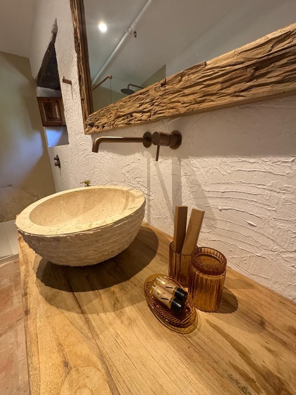 A wooden bowl sink with a wooden handle and a glass container with a cork.