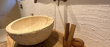 A wooden bowl sink with a wooden handle and a glass container with a cork.