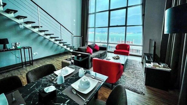Een moderne woonkamer met een trap, een eethoek en een groot raam met uitzicht op de stad.