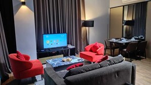 Een moderne hotelkamer met een flatscreen televisie, een zithoek met tafel en stoelen, en een bank.