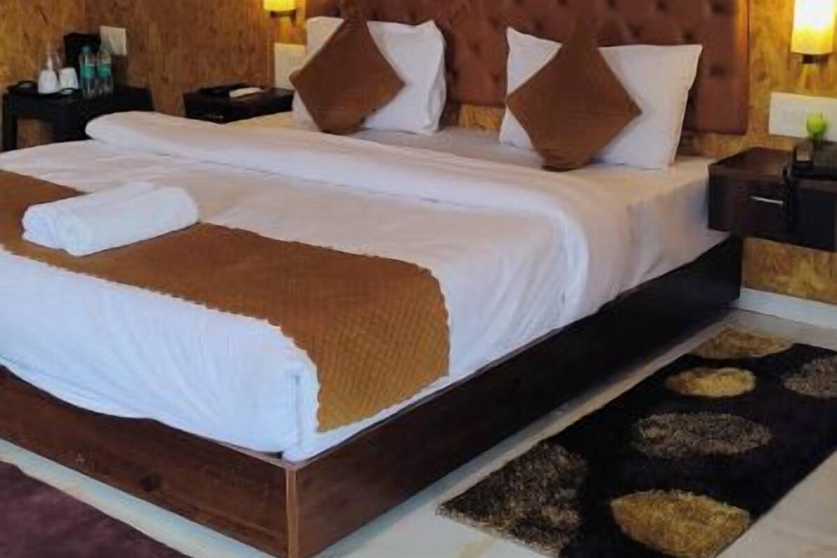 Une chambre d’hôtel avec un grand lit, des murs en bois, une tête de lit moderne et un sol en marbre.