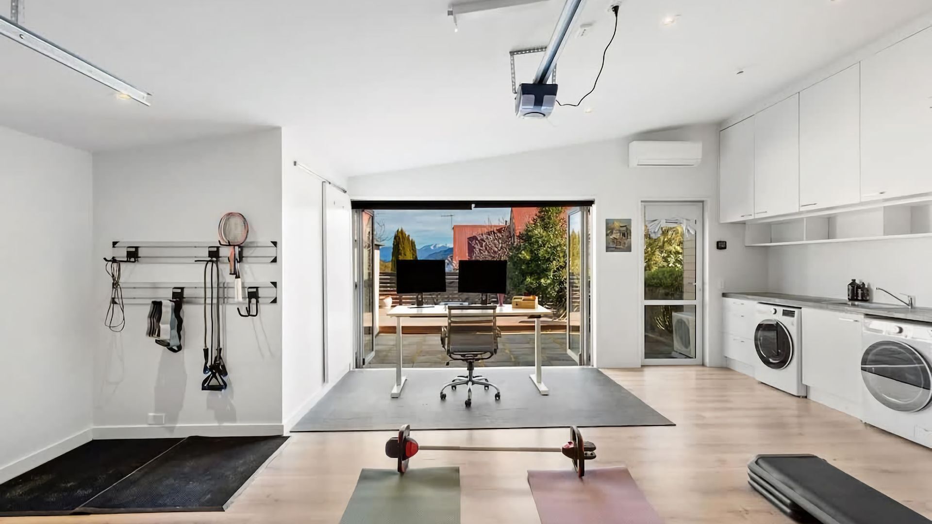 A modern, open-plan living space with a kitchen, workout area, and a view of the outdoors.