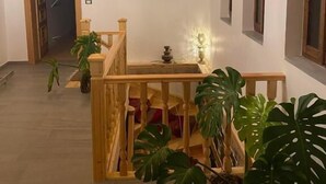 Een houten trap met een leuning, een schilderij aan de muur en potplanten.
